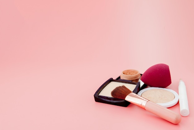 Ensemble de cosmétiques colorés sur une base de fond de table en bois rose pour le maquillage sous la forme d'un espace de copie de coussin