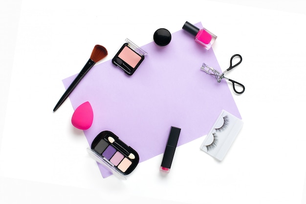 Ensemble de cosmétiques décoratifs professionnels, outils de maquillage et accessoire de couleur rose tendance isolé sur fond violet et blanc Mise à plat