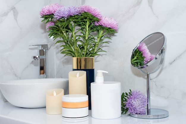 Ensemble de cosmétiques naturels dans un salon de beauté Pots de produit de soin du corps ou des cheveux sur la table avec des fleurs