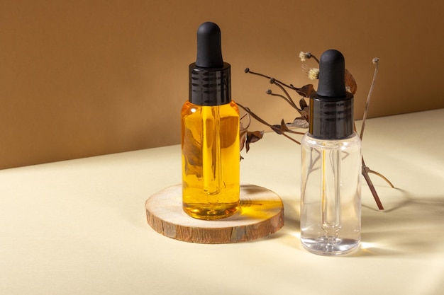 Un ensemble de cosmétiques pour le sauna et le spa. Récipient en verre transparent avec huile naturelle pour le corps et les cheveux sur un support en bois. Conception de style de mise en page. Concept de cosmétologie et de beauté.