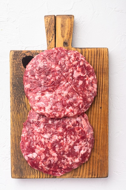 Ensemble de côtelettes de hamburgers de boeuf hachés crus frais fermiers faits maison, sur pierre blanche