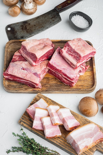 Ensemble de côtes courtes de boeuf cru, avec des ingrédients, et vieux couteau couperet de boucher, sur fond de pierre blanche