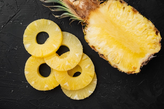 Ensemble de coupe d'ananas, sur fond de table en pierre noire noire, vue de dessus à plat