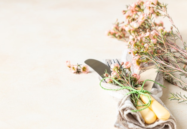 Ensemble de couverts et belles fleurs roses sur table en pierre claire Fête de Pâques