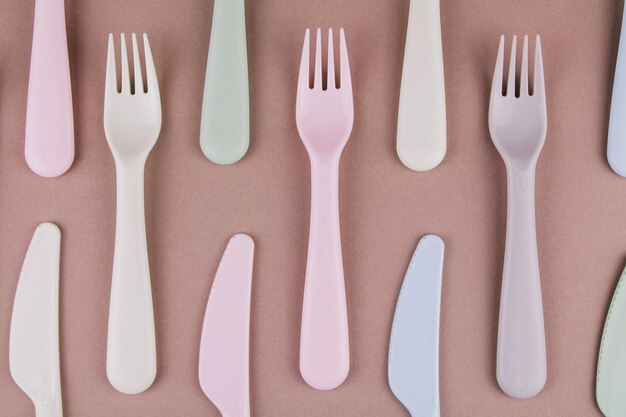 Un ensemble de couverts en plastique de différentes couleurs cuillères fourchettes couteaux sur la table de la cuisine et plastique écologique