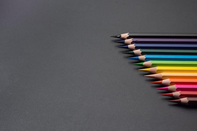 Ensemble de crayons de couleur, rangée de crayons de couleur en bois sur fond noir, pour dessiner