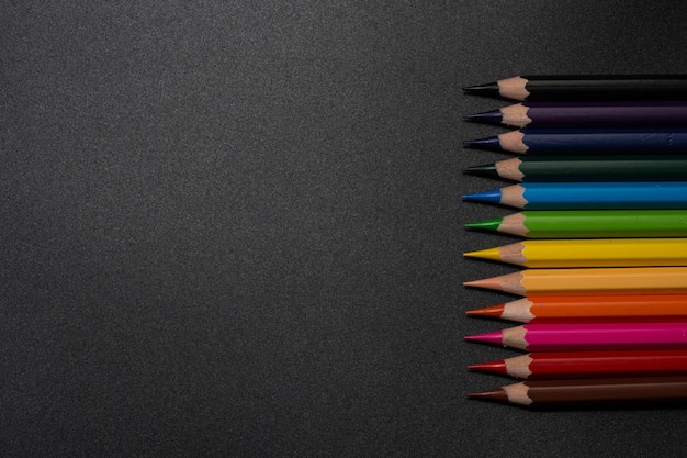 Ensemble de crayons de couleur, rangée de crayons de couleur en bois sur fond noir