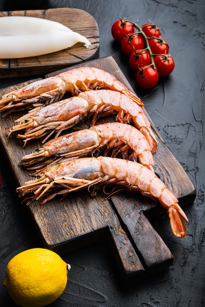 Ensemble de crevettes royales avec des ingrédients pour la paella sur une surface en béton noir, photo alimentaire.