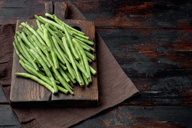 Ensemble de cuisine de haricots verts, sur une planche à découper en bois, sur la vieille table en bois sombre