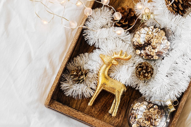 Ensemble de décorations de Noël dans une boîte en bois sur un lit blanc. Notion de vacances. Mise à plat, vue de dessus