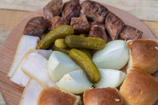 Ensemble de délicieux plats ukrainiens, gros plan. Concombre, oignon, graisse, petit pain et saucisse sur une assiette, vue de dessus