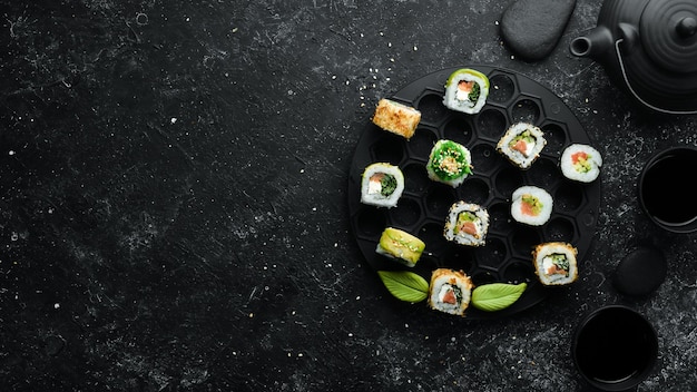 Ensemble de délicieux sushis et makis sur fond de pierre noire Cuisine japonaise Vue de dessus Espace libre pour votre texte