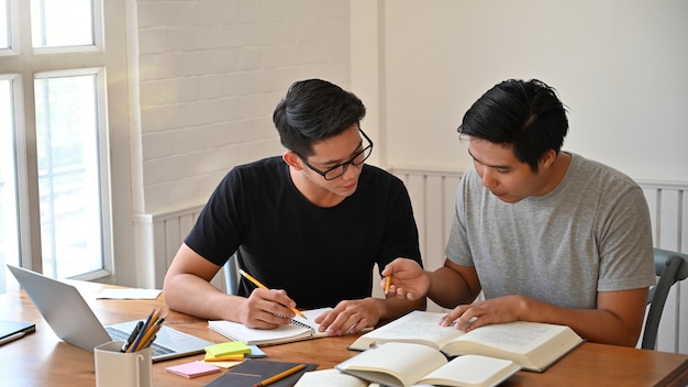 Ensemble de deux hommes avec des livres sur la table.