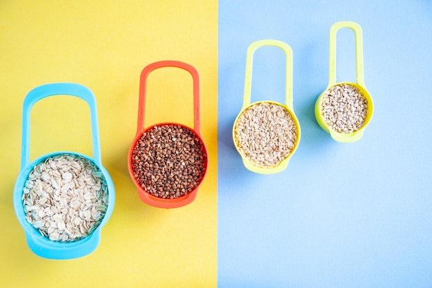 Ensemble de différentes céréales dans des récipients multicolores Farine d'avoine, orge, sarrasin et riz