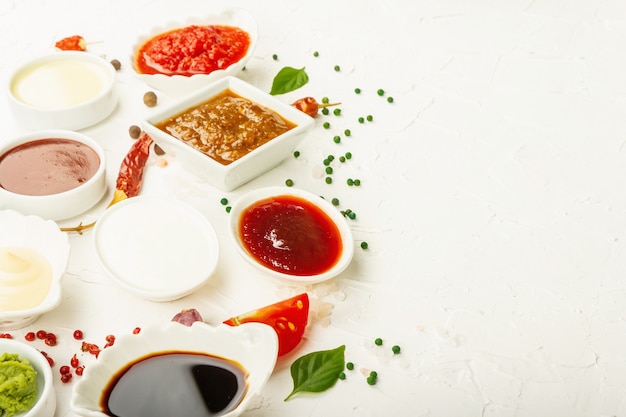 Ensemble de différentes sauces - ketchup, mayonnaise, barbecue, soja, chutney, wasabi, adjika, raifort, aïoli, marinara. Lumière dure à la mode, ombre sombre. Fond de mastic blanc, espace de copie