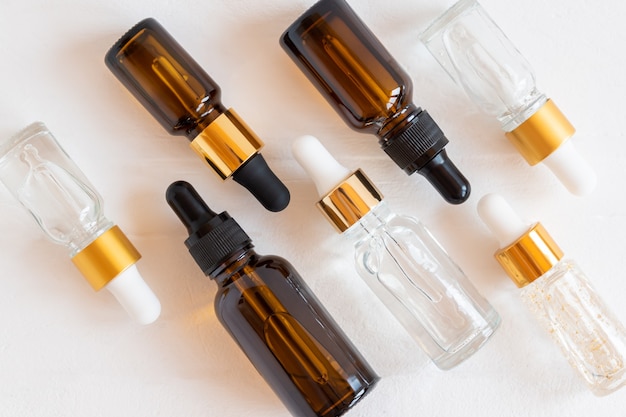 Ensemble de différents flacons compte-gouttes avec sérum de soins de beauté, acide hyaluronique et vitamines sur fond de bois. Cosmétiques à la maison et concept de spa