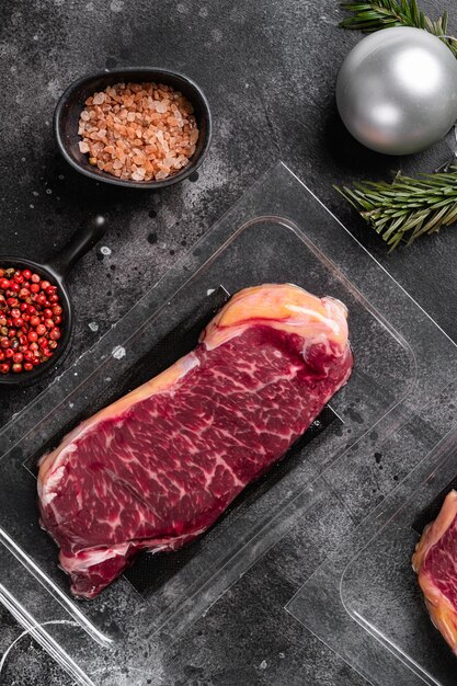 Ensemble d'emballage sous vide de viande, sur fond de table en pierre noire foncée, vue de dessus à plat