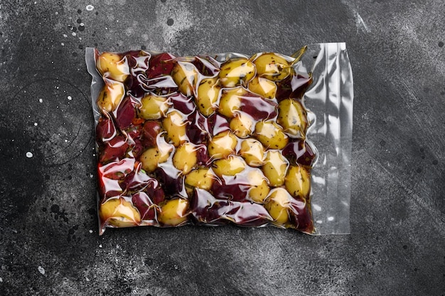 Ensemble d'emballages sous vide d'olives biologiques, sur fond de table en pierre noire noire, vue de dessus à plat