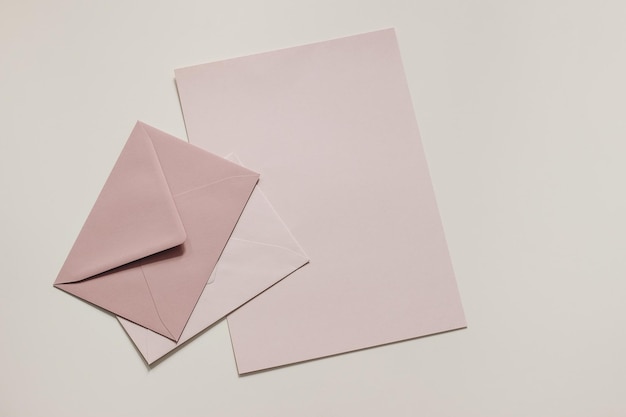 Ensemble d'enveloppes vierges rose pastel et de maquettes de feuilles de papier Fond neutre beige Correspondance postale et concept de poste Papeterie de bureau d'affaires nature morte Vue de dessus à plat