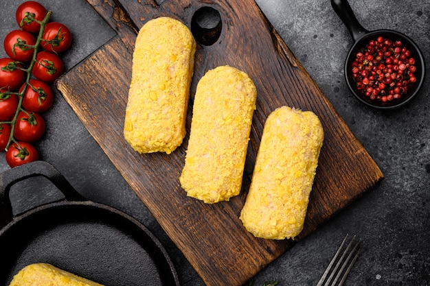 Ensemble d'escalopes de poulet panées crues, sur fond de table en pierre noire noire, vue de dessus à plat