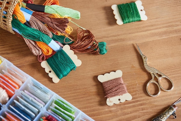 Ensemble de fils multicolores pour ciseaux de point de croix sur une table en bois Concept de couture