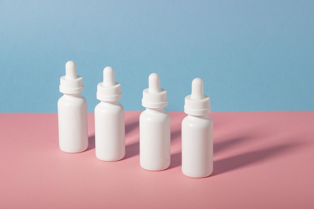 Photo un ensemble de flacons cosmétiques blancs avec un compte-gouttes aligné avec des ombres dures le concept de soins du visage et du corps à la maison et dans un salon de beauté