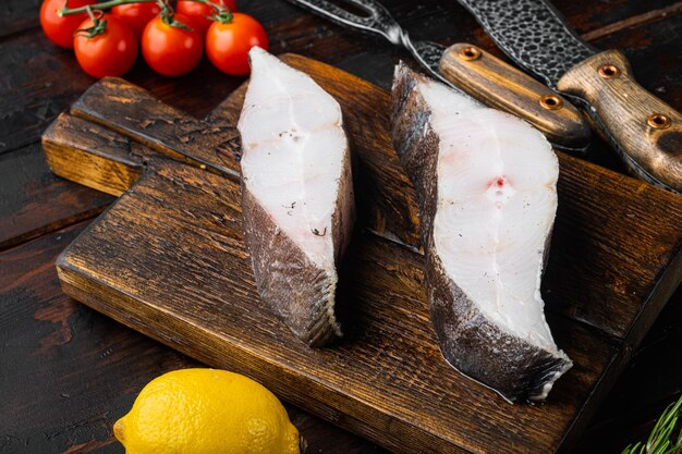 Ensemble de flétan de poisson cru de steak frais, avec des ingrédients et des herbes de romarin, sur un vieux fond de table en bois foncé