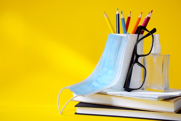 Ensemble de fournitures scolaires, lunettes, désinfectant pour les mains et masque de protection médicale.