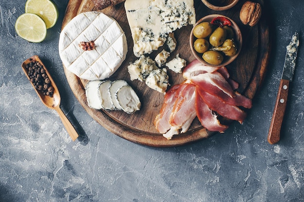 Ensemble de fromage hamon miel olives vertes noix et épices sur planche de bois rustique variété de collations