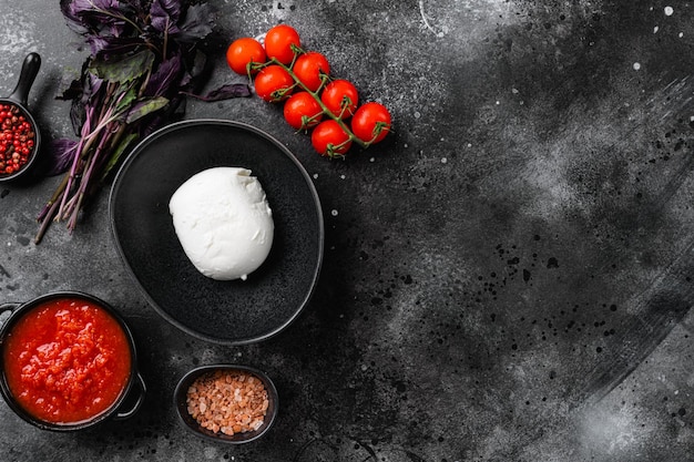 Ensemble de fromages italiens mozzarella, sur fond de table en pierre noire foncée, vue de dessus à plat, avec espace de copie pour le texte