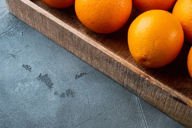 Ensemble de fruits orange mûrs, dans une boîte en bois, sur une table en pierre grise