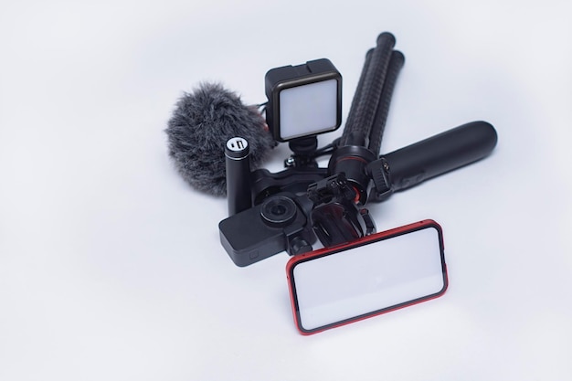 Ensemble de gadgets de blogging Maquette de smartphone avec un écran blanc avec une banque d'alimentation pour trépied avec une caméra d'action et un stabilisateur avec un microphone sur fond blanc