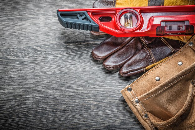 Ensemble de gants de protection de niveau construction ceinture à outils en cuir sur planche de bois.