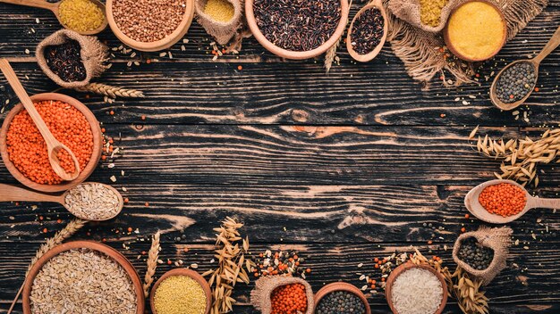 Ensemble de gruaux et céréales sarrasin lentilles riz millet orge maïs riz noir sur un fond en bois vue de dessus espace de copie