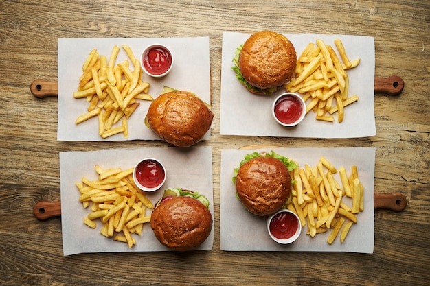 Ensemble de hamburgers avec frites et sauce ketchup. Gros hamburgers et frites sur fond de table en bois. Fond de jeu de restauration rapide. Carte du restaurant burger