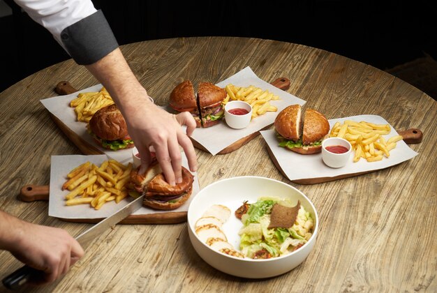 Ensemble de hamburgers avec frites et sauce ketchup. Gros hamburgers et frites sur fond de table en bois. Fond de jeu de restauration rapide. Carte du restaurant burger