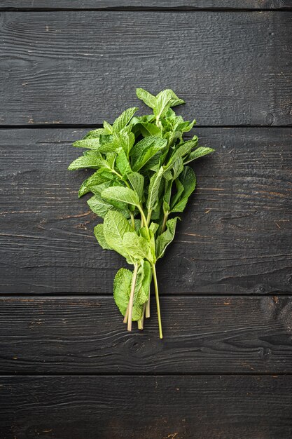 Ensemble d'herbes de feuilles de menthe fraîche, sur fond de table en bois noir, vue de dessus à plat