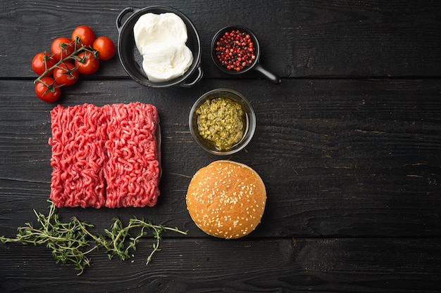 Ensemble d'ingrédients hamburger aux boulettes de viande, sur une table en bois noire, vue de dessus à plat