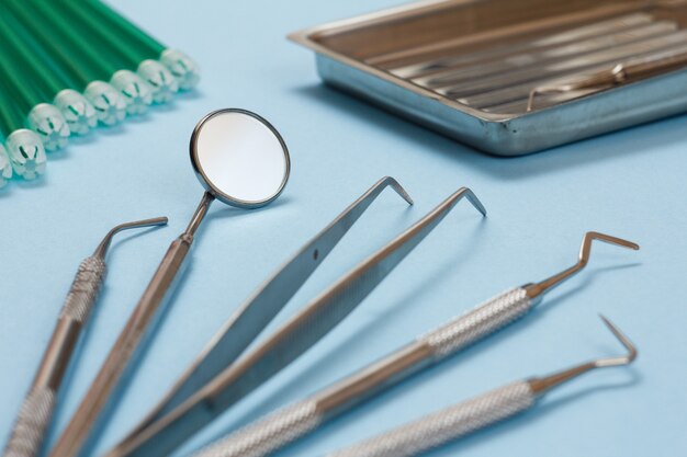 Ensemble d'instruments de remplissage composites pour traitement dentaire et éjecteurs de salive. Outils médicaux sur fond bleu.