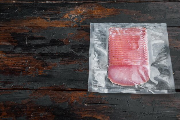 Ensemble de jambon de porc à la viande séchée, emballé sous vide, sur un vieux fond de table en bois foncé, avec espace de copie pour le texte