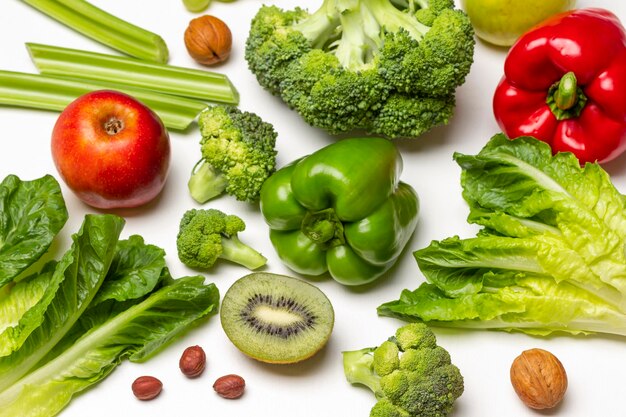 Ensemble de légumes brocoli poivre laitue tiges de céleri pomme moitié kiwi et noix