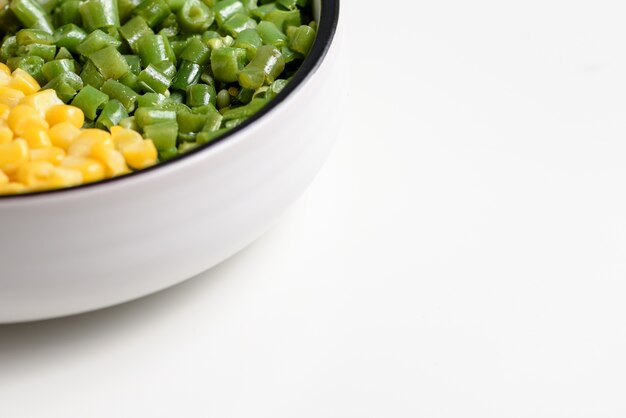 Ensemble de légumes à deux couleurs: grain vert coupé en dés et noyau de maïs jaune, sur fond blanc avec espace négatif.