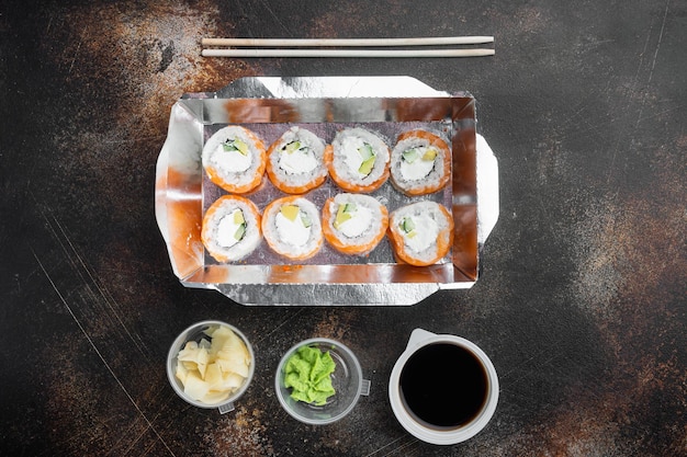 Ensemble de livraison de rouleaux de sushi, sur un vieux fond rustique sombre, vue de dessus à plat, avec espace pour copie et espace pour le texte