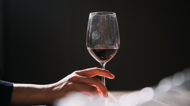 Ensemble de mains tenant un verre de vin rouge isolé sur fond noir