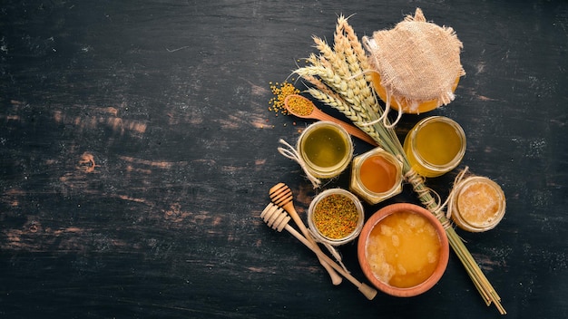 Un ensemble de miel et de produits apicoles Miel en nid d'abeille Sur un fond en bois noir Espace libre pour le texte Vue de dessus