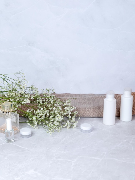 Ensemble minimaliste et élégant de produits blancs doux et légers pour les soins du corps et du visage et d'accessoires de bain avec des fleurs blanches sèches dans un intérieur doux et léger