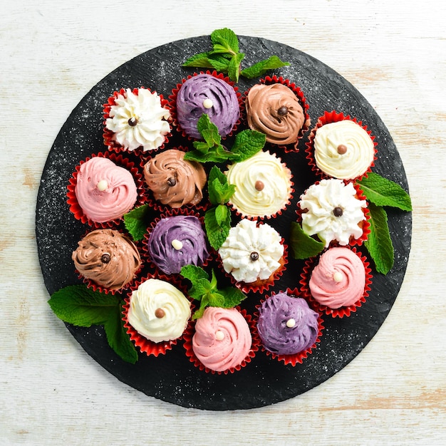 Ensemble de muffins à la crème colorés sur une plaque noire à la menthe Vue de dessus Style rustique