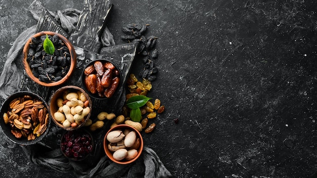 Ensemble de noix et de fruits secs et de baies sur fond de pierre noire Vue de dessus Espace libre pour votre texte