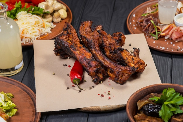 Ensemble de nourriture avec des côtes de porc grillées sur fond de bois noir