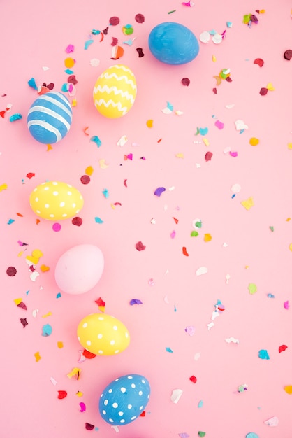 Photo ensemble d'oeufs de pâques entre confettis colorés